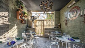 A dining area with round tables, clear chairs, and a chandelier.
