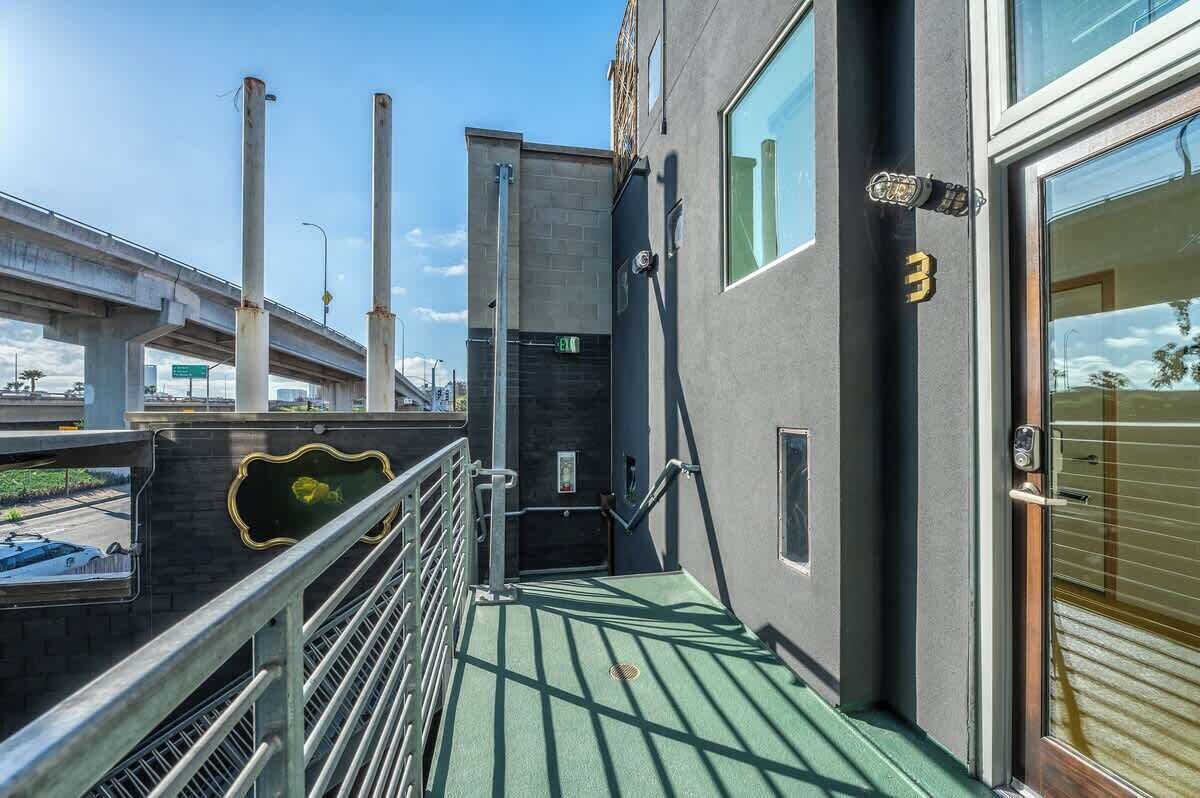 Un bâtiment moderne doté d’un toit végétalisé, d’une rambarde en métal et d’une porte avec une plaque numérotée.