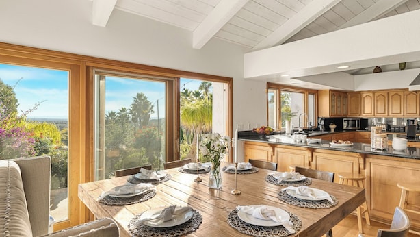 A spacious kitchen with wooden cabinets, a large island, and a view of the outdoors. - The Tennis Ranch by Avantstay Resort-style Estate Pool + Game Room + Tennis Court Near Wineries (Escondido)