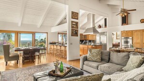 A spacious living area with a large sofa, a dining table with chairs, and a kitchen with wooden cabinets and a stainless steel refrigerator. - The Tennis Ranch by Avantstay Resort-style Estate Pool + Game Room + Tennis Court Near Wineries (Escondido)