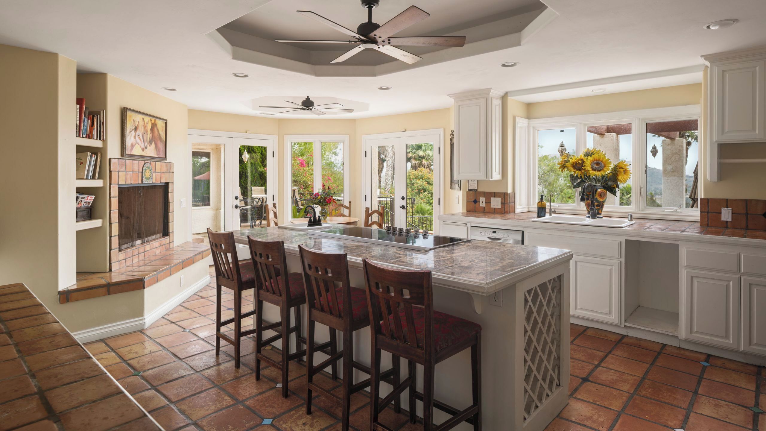 A spacious kitchen with a large island, white cabinetry, and a view of the outdoors.