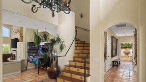 Un interior amplio con una escalera, una araña y un televisor.
