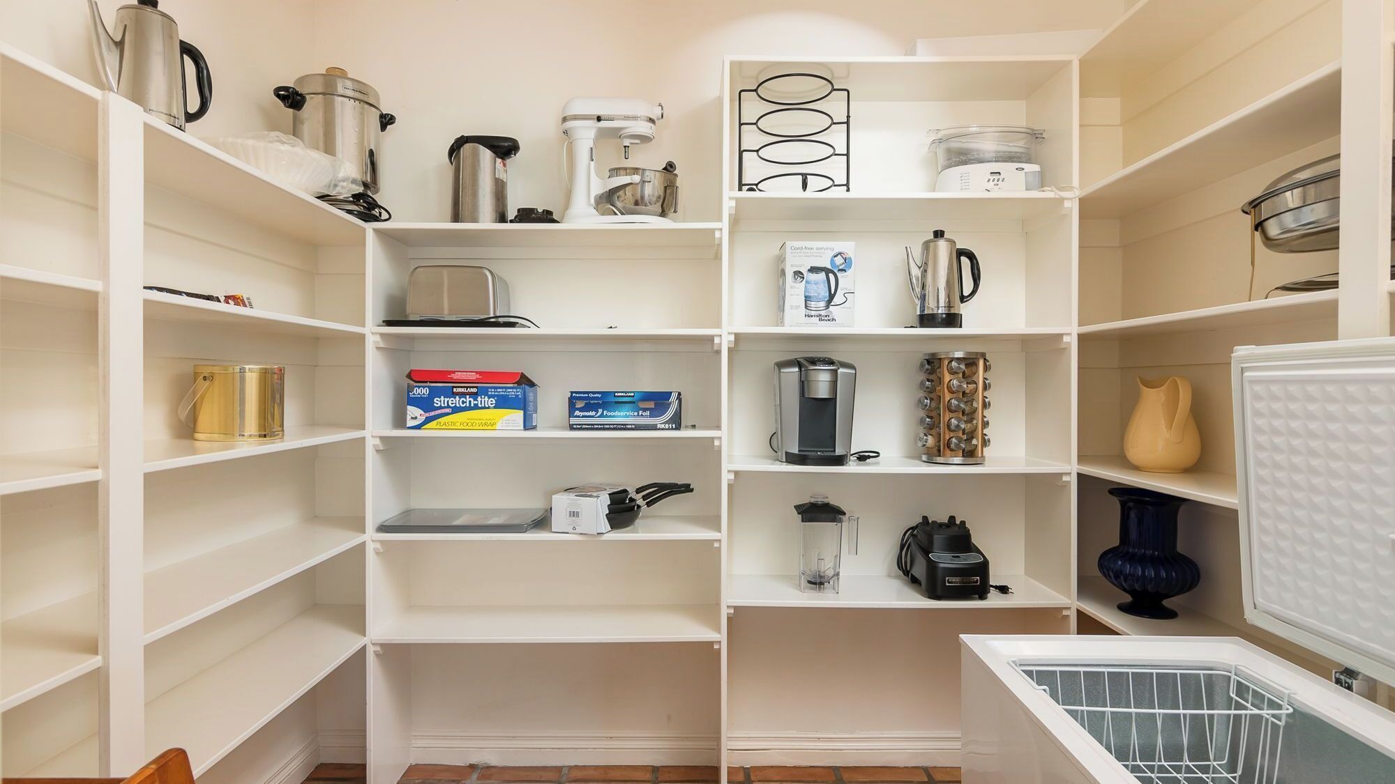 Een overzichtelijke keuken met diverse apparaten en keukengerei op open planken.