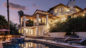 A multi-story house with a swimming pool, outdoor seating, and a staircase leading to the upper levels.