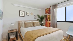 Een verzorgde hotelkamer met een bed, nachtkastje, lamp en een stoel.