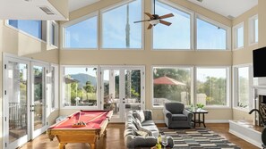 A spacious living room with a pool table, a sofa, a chair, and a fireplace.