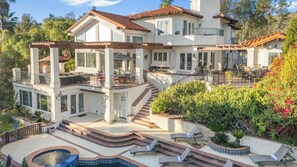 A multi-story house with a patio, outdoor seating, and a swimming pool.