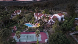 An aerial view of a residential area with houses, a tennis court, and a swimming pool.