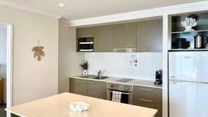A modern kitchen with a central island, stainless steel appliances, and a white tiled backsplash. - Amazing Water View Apartment - Pool, Gym, Parking. (Urangan)