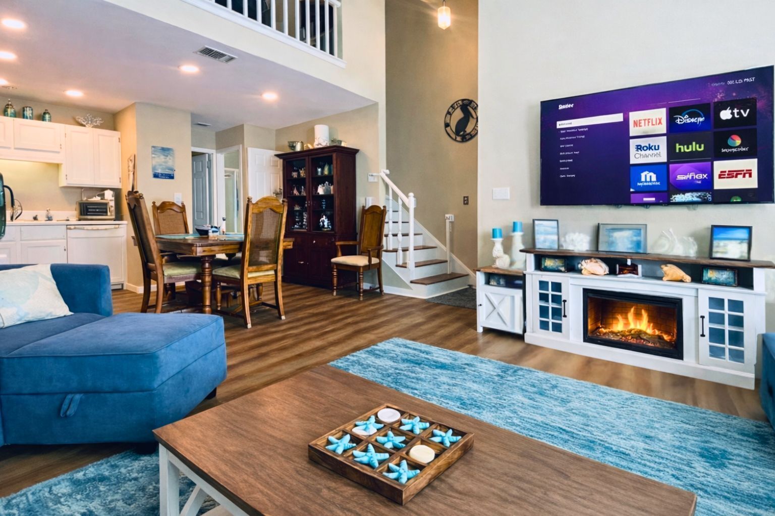 Open-concept living space with high ceilings, loft overlook, fireplace, and seam