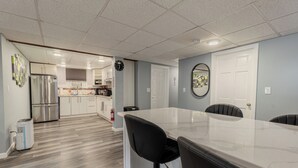 Une cuisine moderne dotée d’un îlot central, d’appareils électroménagers en acier inoxydable et d’un coin repas avec des tabourets de bar.