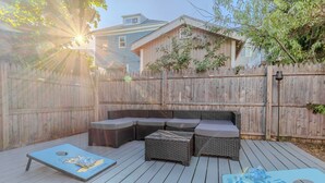 Une terrasse en bois avec un canapé modulable et deux jeux de lancer d’anneaux.