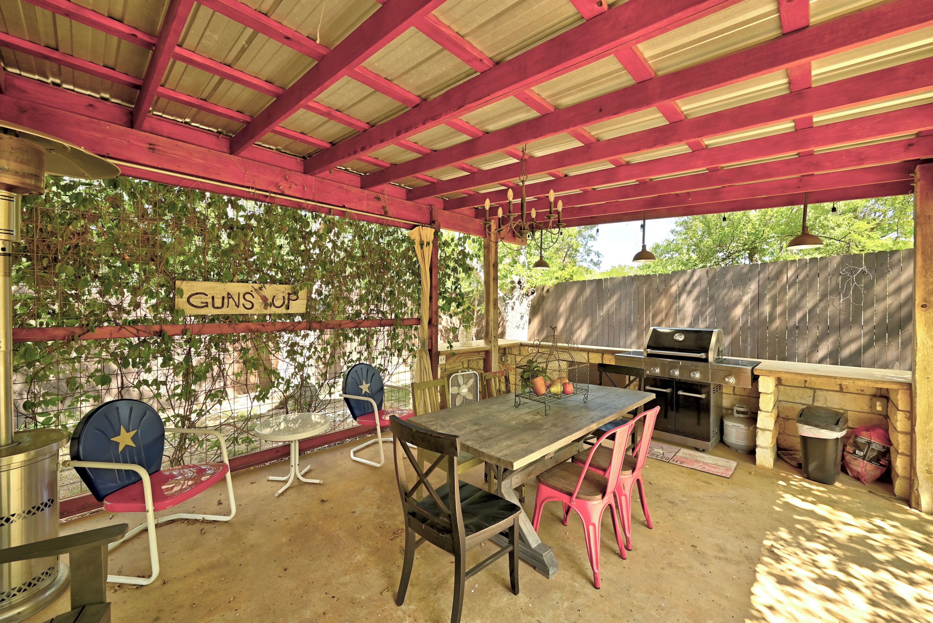 Une terrasse extérieure avec une table et des chaises, un barbecue et un panneau sur lequel on peut lire : « ARMES AU VENT ».