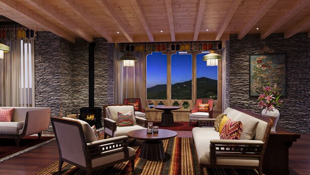 A cozy room with stone walls, a fireplace, comfortable seating, and large windows with a mountain view.