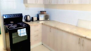 Une cuisine équipée d’une cuisinière, d’un four à micro-ondes et de placards.