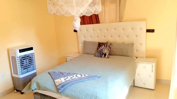 Une chambre à coucher comprenant un lit, une table de chevet, une commode, un radiateur et une moustiquaire.