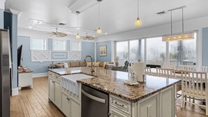 A spacious kitchen with a large island, white cabinetry, and pendant lighting. - 571 Seabatical: Canal Front With Pool! (Fort Myers Beach)