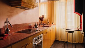 Une cuisine avec des meubles de rangement en bois, un évier, une cuisinière et une fenêtre ornée de rideaux jaunes.