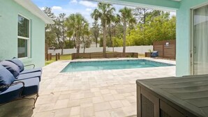 Un jardin avec une piscine, une terrasse couverte et une clôture en bois.