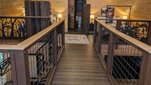 A wooden interior with a central staircase, metal railings, and a ceiling fan. - Bar Harbor Cabin with Treehouse Suite & Hot Tub (Hancock)