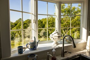A kitchen with a window, a sink, and various kitchen items on the windowsill.