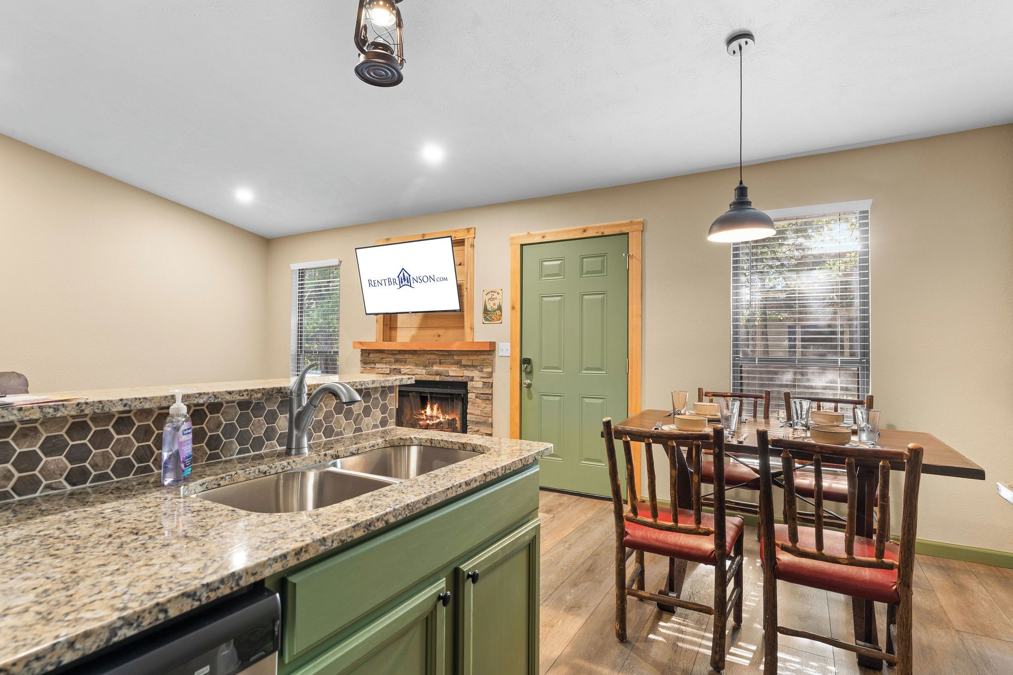 A kitchen with a stone countertop, a sink, a dining table with chairs, and a green door.