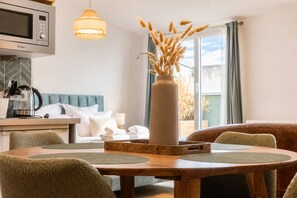 A modern kitchen with a microwave, kettle, and dining area with a wooden table and chairs. - Bright Apartment in the City Centre, Terrace, A/C (Bordeaux)