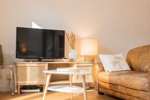 A living room with a flat-screen TV, a lamp, a sofa, and a small table. - Bright Apartment in the City Centre, Terrace, A/C (Bordeaux)