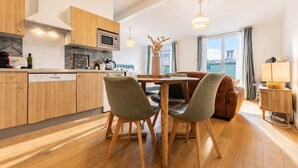 A modern kitchen with wooden cabinets, a microwave, and a dishwasher. There is a dining area with a wooden table and chairs. - Bright Apartment in the City Centre, Terrace, A/C (Bordeaux)