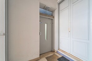 A hallway with a closed door, a small window, and a mat at the entrance.