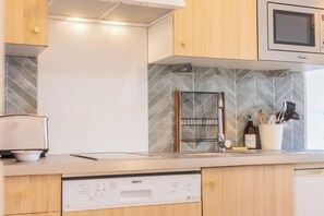A modern kitchen with a built-in microwave, a dishwashing station, and a tiled backsplash. - Bright Apartment in the City Centre, Terrace, A/C (Bordeaux)