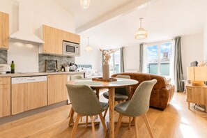 A modern kitchen with a dining area, wooden cabinets, and a view of the outdoors. - Bright Apartment in the City Centre, Terrace, A/C (Bordeaux)
