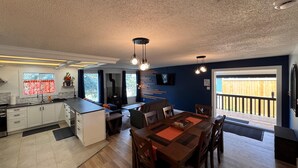 Una cocina moderna con una isla central, comedor con muebles de madera y un amplio ventanal con vistas.