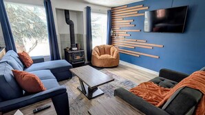 Una sala moderna con un sofá modular, una mesa de centro, un sillón informal y una chimenea.