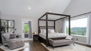 Een slaapkamer met een hemelbed, een bankje, een sofa en uitzicht op het omliggende landschap.