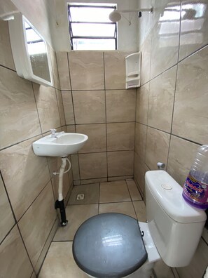 A small, tiled bathroom with a toilet, sink, and a window. - Furnished apartment in Coroado in Manaus. With bed, stove, bathroom, Wi-fi… (Manaus)