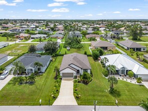 A residential neighborhood with houses, lawns, and a clear sky. - Charming, Comfort and Relaxation Await! - Casa Bella - Roelens (Cape Coral)