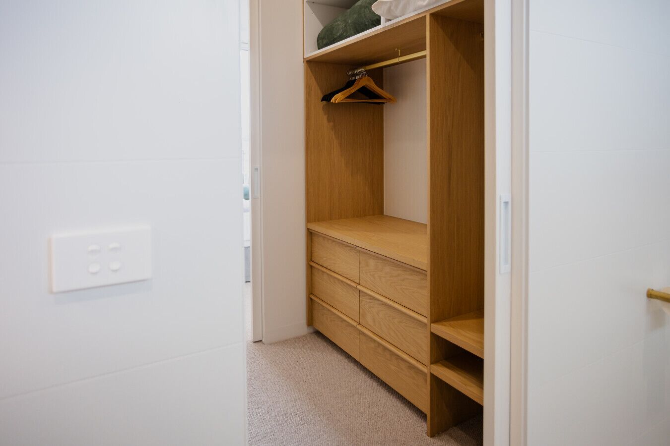 A walk-in closet with wooden shelving and a hanging rod.