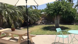 An outdoor patio with a wooden picnic table, a metal umbrella, and a metal chair. - Stylish Comfy 4-Bedroom House in Anaheim - Close to Disney! (Anaheim)