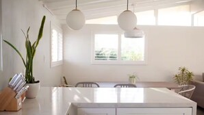 A modern kitchen with a central island, pendant lights, and a view of the outdoors. - Stylish Comfy 4-Bedroom House in Anaheim - Close to Disney! (Anaheim)