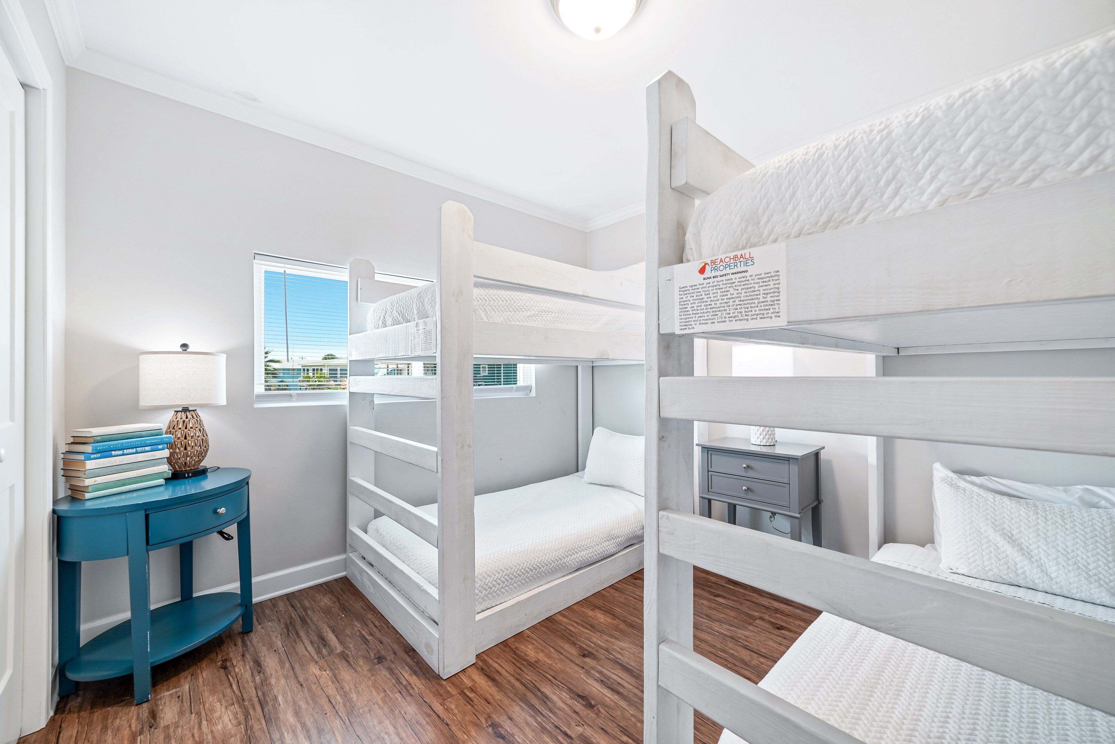 Dormitorio con literas, una ventana, escritorio con libros y una lámpara.