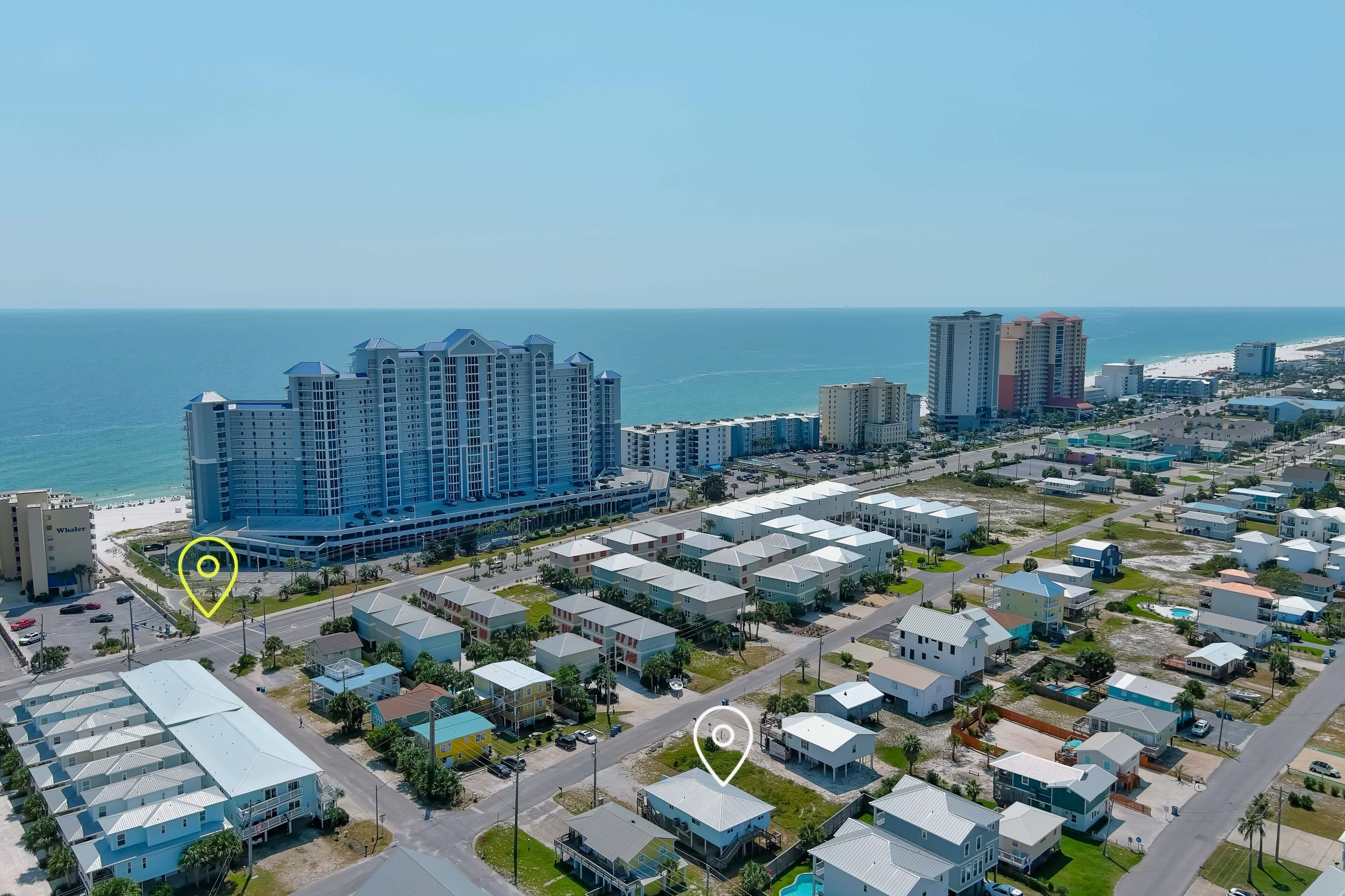 An aerial view of a coastal residential area with multiple high-rise hotels and single-family homes.