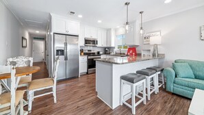 A modern kitchen with white cabinetry, stainless steel appliances, and a central island with bar stools.