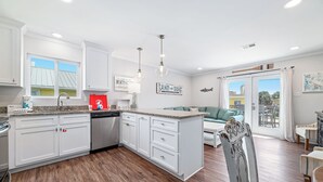 A modern kitchen with white cabinetry, a granite countertop, and a dishwasher.