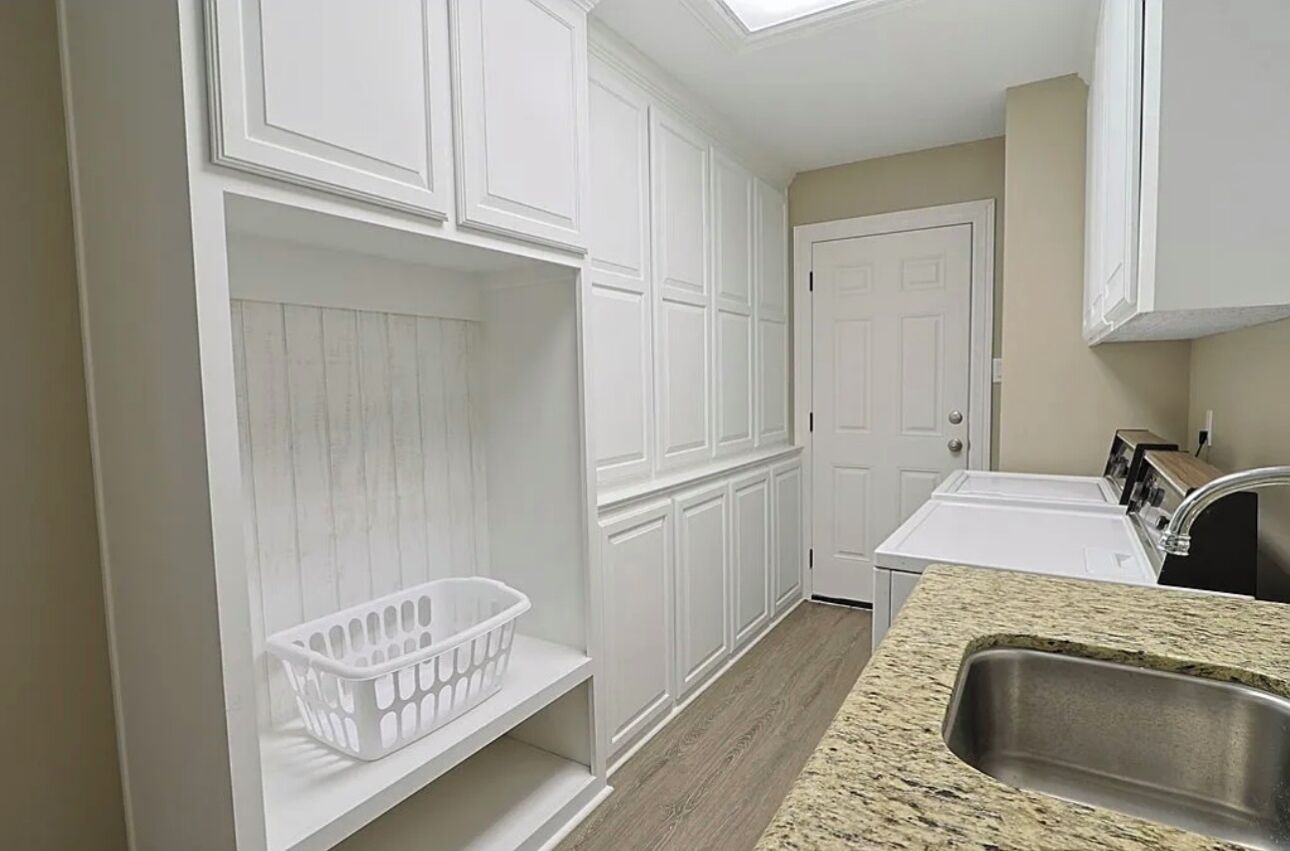 A kitchen with white cabinetry, a granite countertop, and a stainless steel sink.
