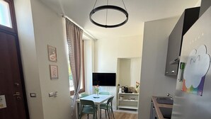 A modern kitchen with a built-in refrigerator, a dining area with a table and chairs, and a TV mounted on the wall.