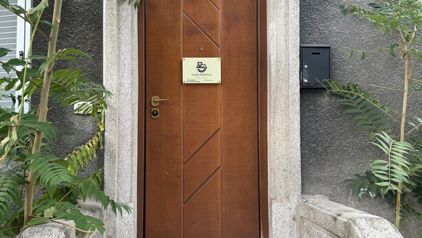 A wooden door with a sign for 'Tux300 Properties' and a doormat with a dog silhouette.