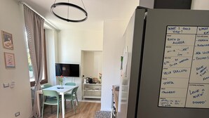 A modern kitchen with a refrigerator, dining table, and chairs.