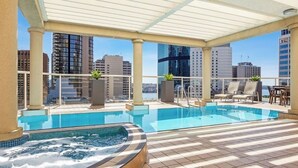 A rooftop pool with a hot tub, lounge chairs, and potted plants. - KozyGuru | Sydney CBD | Modern City Retreat (Sydney)