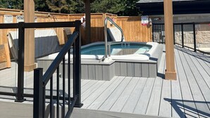 A wooden deck with a hot tub, a covered seating area, and a pool.